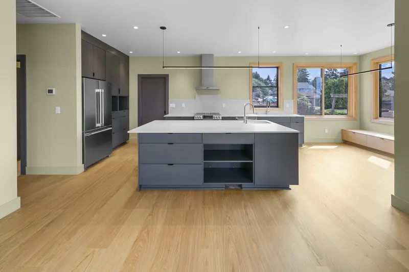 Open kitchen and dining area with a large island and oak floors in a new Seattle home